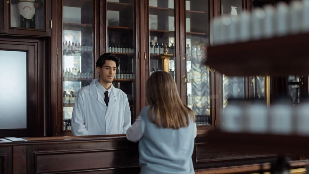 Farmacéutico atendiendo a una clienta en el mostrador